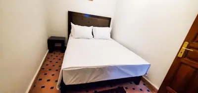 a small bedroom with a bed with white sheets and pillows at Riad 1954 in Marrakech
