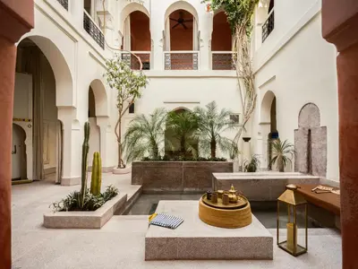 a courtyard with a fountain in a building with palm trees at Riad Brummell Medina in Marrakech