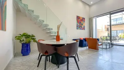 a room with a table and chairs and a staircase at Duplex Zoé - Contemporain et design à Marrakech in Marrakech