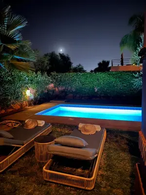 a swimming pool at night with two lounges and two beds at Villa Magnolia - Amelkis Golf in Marrakech