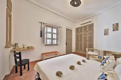 a bedroom with a bed and a table and a chair at Riad Al Badia in Marrakech