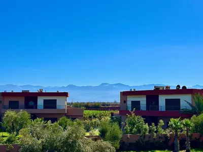 two houses in a field with mountains in the background at Konouz Palace in Marrakech