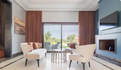 a living room with white chairs and a fireplace at Konouz Palace in Marrakech
