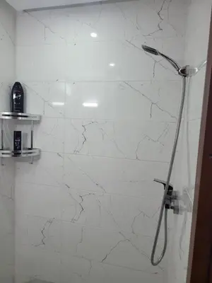 a shower in a bathroom with a white marble wall at Magnifique appartement duplex à 5min de l'aéroport de Marrakech in Marrakech