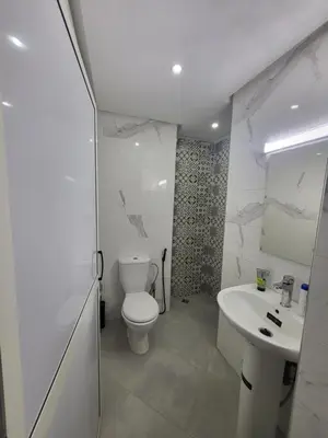 a white bathroom with a toilet and a sink at Magnifique appartement duplex à 5min de l'aéroport de Marrakech in Marrakech