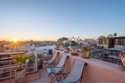 a group of chairs sitting on a balcony with the sunset at Riad Dar Azal in Marrakech