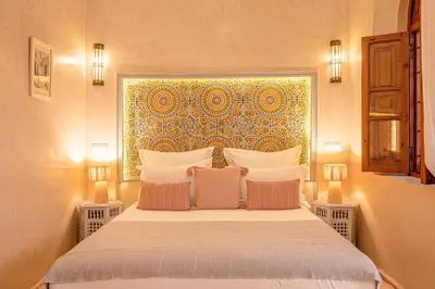 a bedroom with a large bed with two lamps at Riad Dar Azal in Marrakech