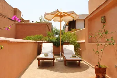 two chairs and an umbrella on a patio at Riad El Morocco Hotel in Marrakech