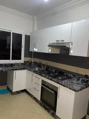 a kitchen with white cabinets and a black counter top at belle appartement a Marrakech in Marrakech