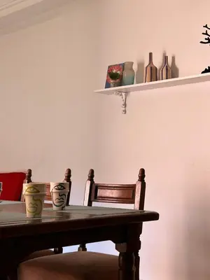 a dining room table with two chairs and a shelf with vases at belle appartement a Marrakech in Marrakech