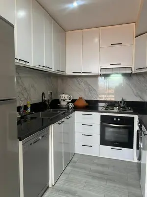 a kitchen with white cabinets and black counter tops at Appartement Marrakech Gueliz 5 Min Drive to City Center in Marrakech