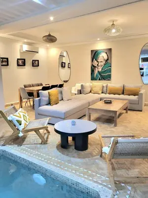 a living room with a couch and a table and a pool at Riad Melilo avec piscine chauffée in Marrakech