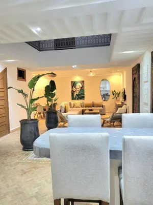 a living room with a table and chairs at Riad Melilo avec piscine chauffée in Marrakech