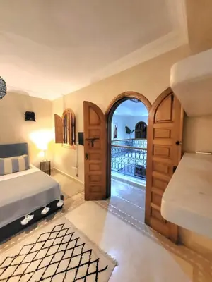 a bedroom with a bed and an open door at Riad Melilo avec piscine chauffée in Marrakech