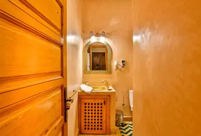 a bathroom with a wooden door and a sink at Riad N 15 Zefriti in Marrakech