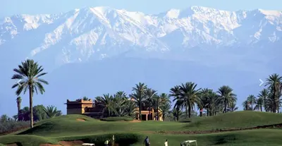 a house on a golf course with mountains in the background at Villa Jude in Marrakech