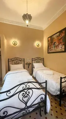 a bedroom with two beds and a painting on the wall at RIAD GJULJA in Marrakech