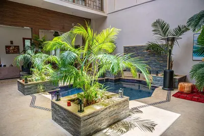 a room with a pool with palm trees in it at Riad Kenza in Marrakech