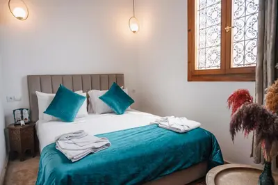 a bedroom with a bed with blue sheets and a window at Riad Kenza in Marrakech