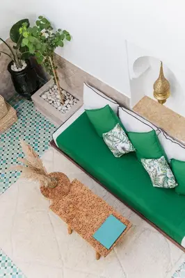 a bed with green and white pillows on the floor at Riad of the Moon in Marrakech