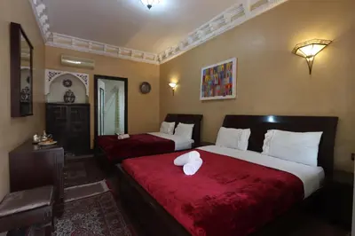 a hotel room with two beds with red sheets at HOTEL CTM in Marrakech
