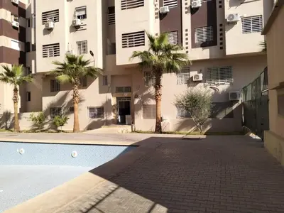 a building with palm trees in front of a swimming pool at Entre ville et détente- les portes de Guéliz in Marrakech