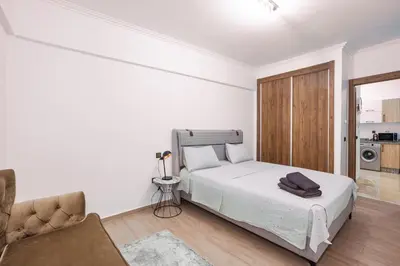 a white bedroom with a bed and a chair at appartement piscine proche gare in Marrakech