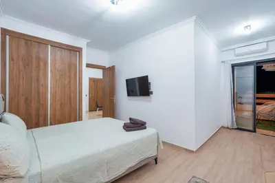 a white bedroom with a bed and a tv at appartement piscine proche gare in Marrakech