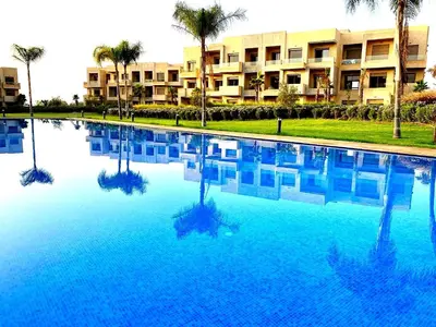 a large swimming pool with palm trees in front of a building at Havre de Paix Piscine Lagon & parc in Marrakech