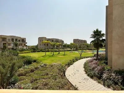 a walkway through a park with palm trees and buildings at Havre de Paix Piscine Lagon & parc in Marrakech
