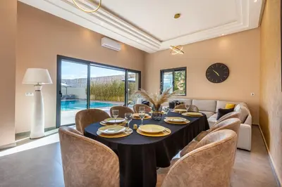 a dining room with a table and chairs and a clock at Villa Dalia, Personnels et option piscine in Marrakech