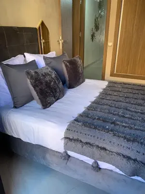 a bed with many pillows on top of it at Appartement neuf climatisé, centre Marrakech. in Marrakech