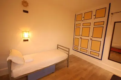 a room with a bed with a light on the wall at El Boussouni Hostel in Marrakech