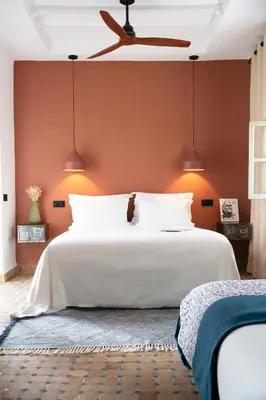 a bedroom with a white bed with orange walls at Riad Al Uzza in Marrakech