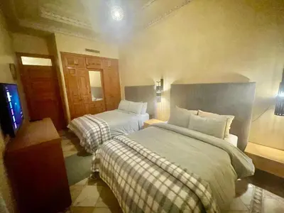 a hotel room with two beds and a television at Les Fleurs du Bien - Marrakech in Marrakech