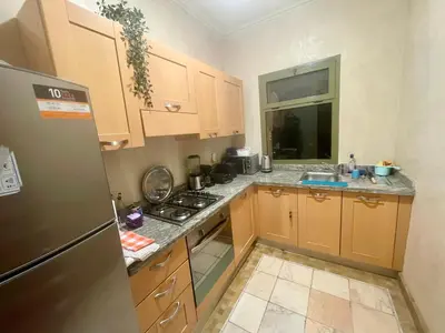 a kitchen with wooden cabinets and a stainless steel refrigerator at Les Fleurs du Bien - Marrakech in Marrakech