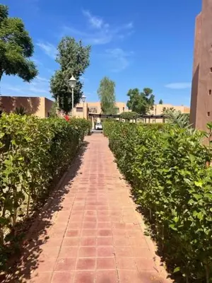 a red brick pathway with bushes and a building at Merveilleuse Marrakech! in Marrakech