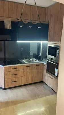 a kitchen with wooden cabinets and a sink and a microwave at Résidence Elsalam Marrakech in Marrakech