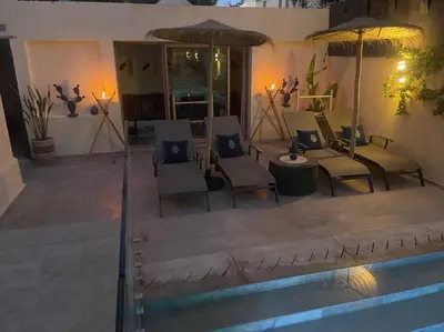 a patio with chairs and umbrellas next to a pool at Villa Bohème avec personnel de maison in Marrakech