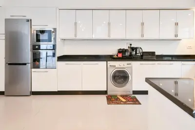 a kitchen with white cabinets and a washing machine at Villa Bohème avec personnel de maison in Marrakech