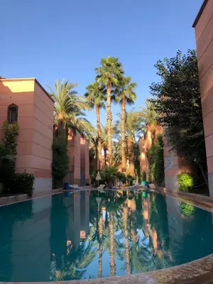 a pool in the middle of a building with palm trees at Riad Ramona lQariya seyaheya in Marrakech
