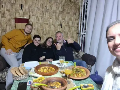 a group of people sitting around a table with food at Riad Ramona lQariya seyaheya in Marrakech