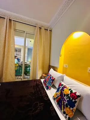 a bedroom with a bed with a yellow headboard and pillows at DAR AL NOUR in Marrakech