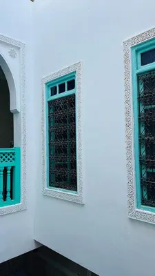 a white wall with two windows with green at DAR AL NOUR in Marrakech