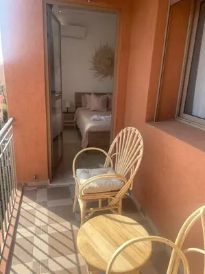 a balcony with chairs and a bed in a bedroom at Bel appart wifi balcon et parking Marrakech centre in Marrakech