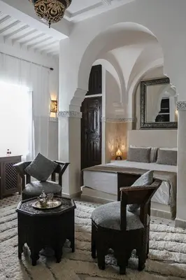 a bedroom with a bed and a chair and a table at RIAD ELNOUJOUM in Marrakech