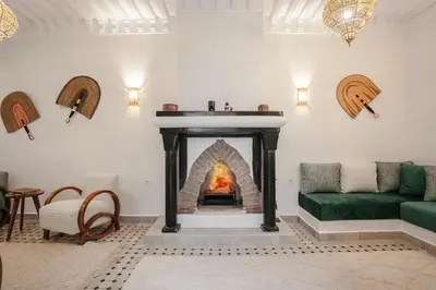 a fireplace in a living room with a green couch at RIAD ELNOUJOUM in Marrakech