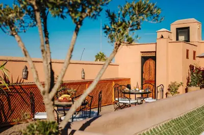 a patio with a table and chairs and a building at RIAD ELNOUJOUM in Marrakech