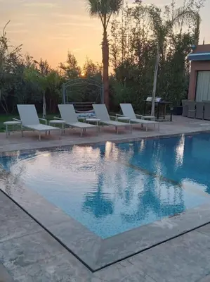 a group of chairs sitting next to a swimming pool at Private Villa with private Chef optional in Marrakech