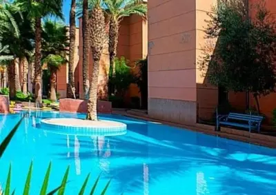a swimming pool with a palm tree in front of a building at maison noé , residence al quaria ab40 in Marrakech
